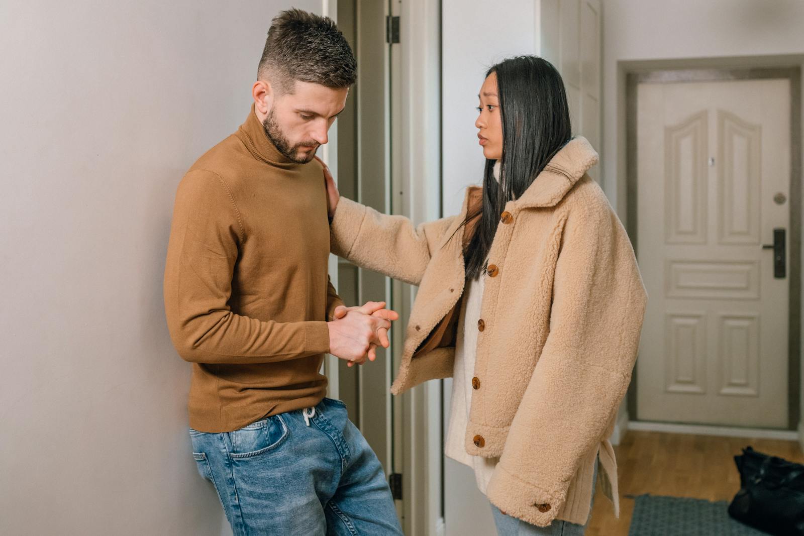 An interracial couple engaged in a serious conversation inside a home, showcasing emotion and connection.