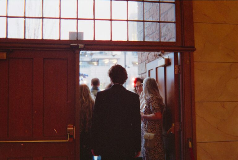 People entering through a large wooden doorway.