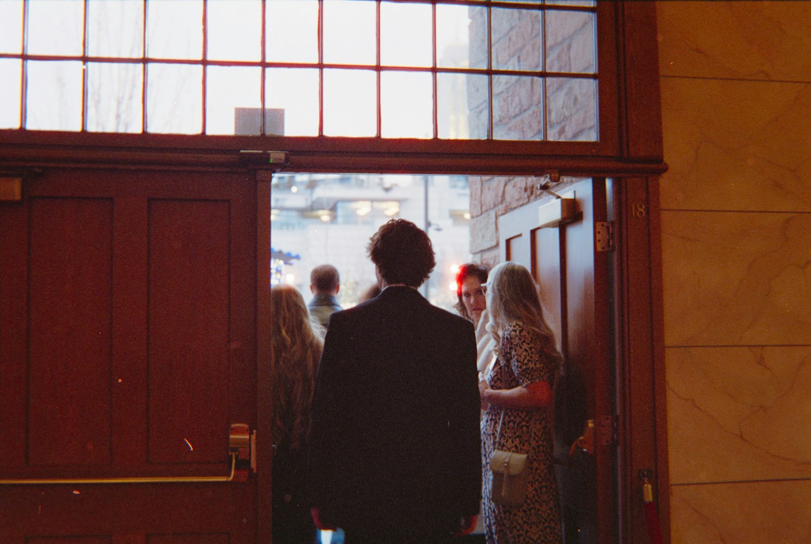 People entering through a large wooden doorway.