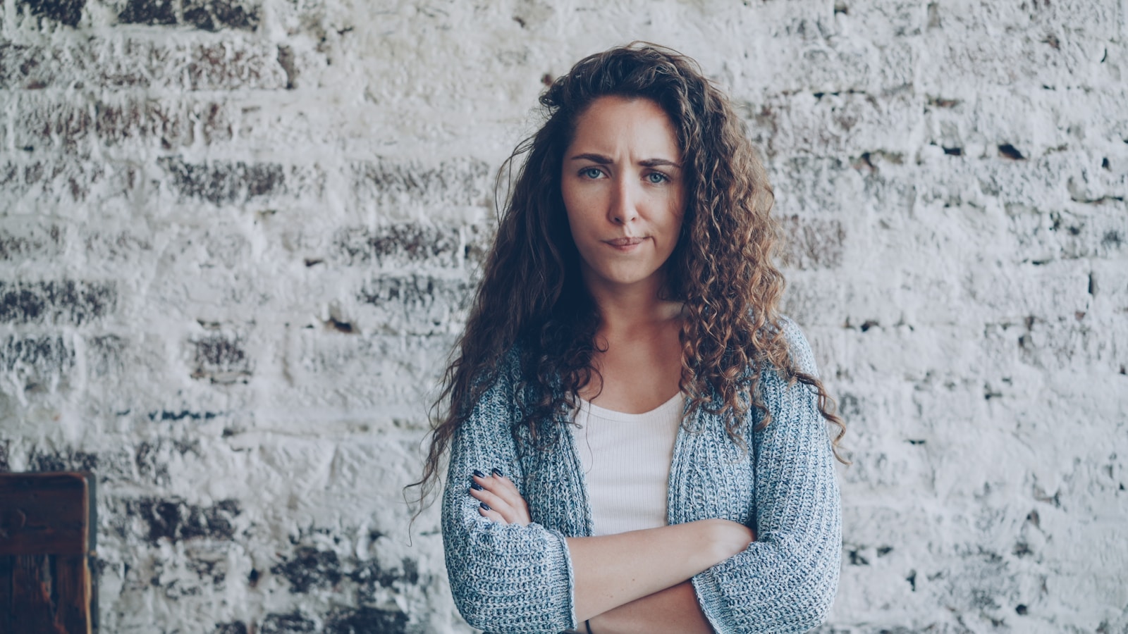 Woman with curly hair standing with arms crossed.