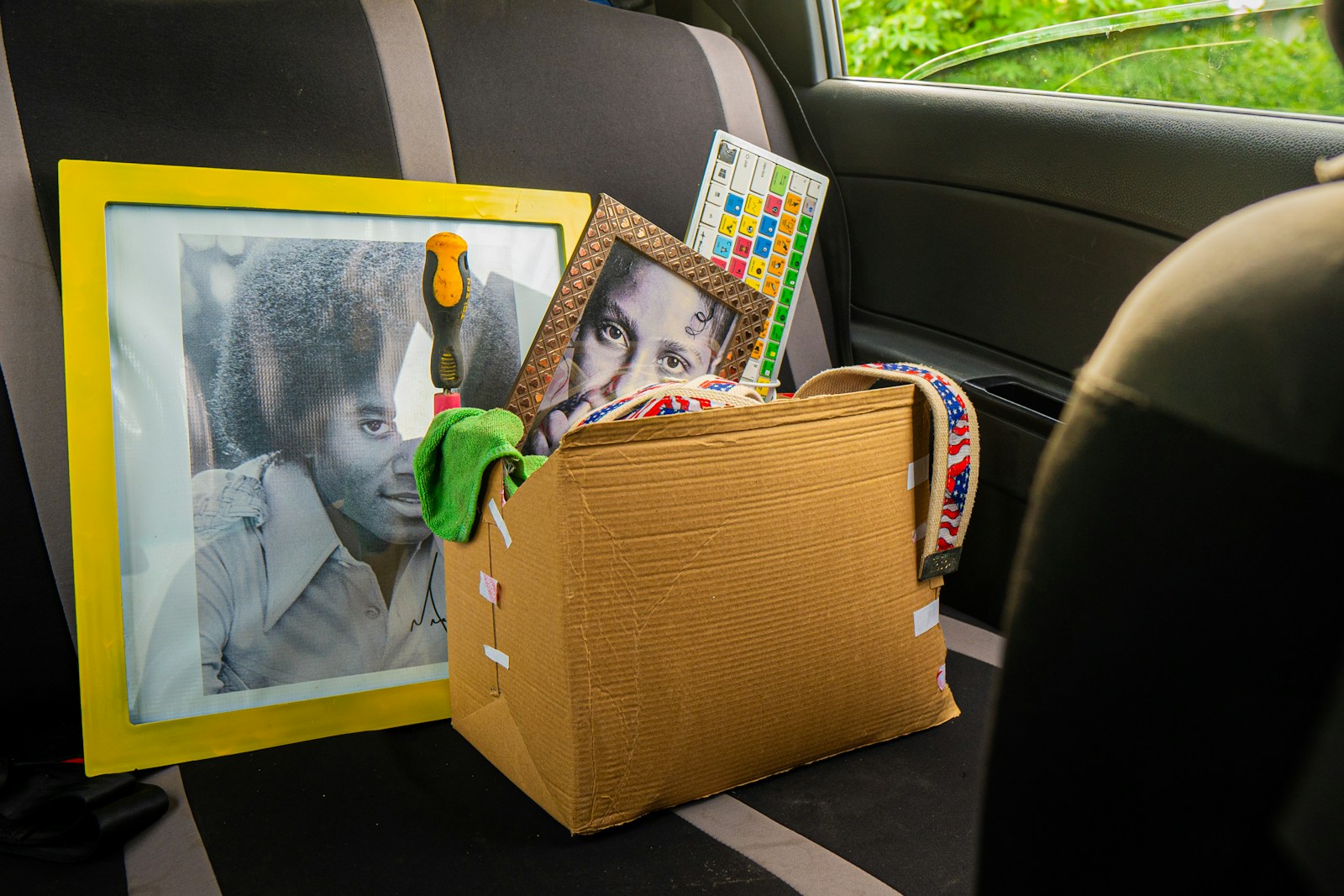 Box of items and framed pictures in car backseat