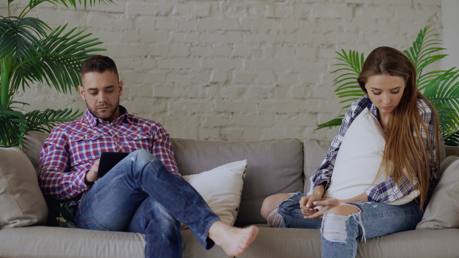 Couple sitting on sofa looking at phones