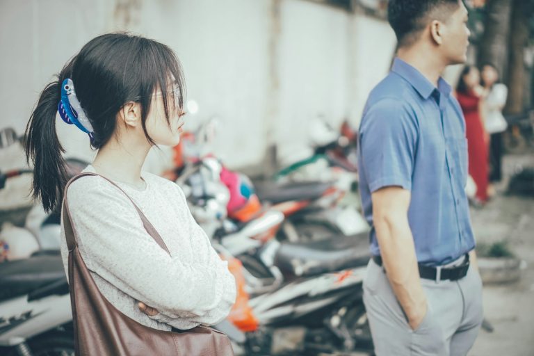 Young couple looking away from each other outdoors.