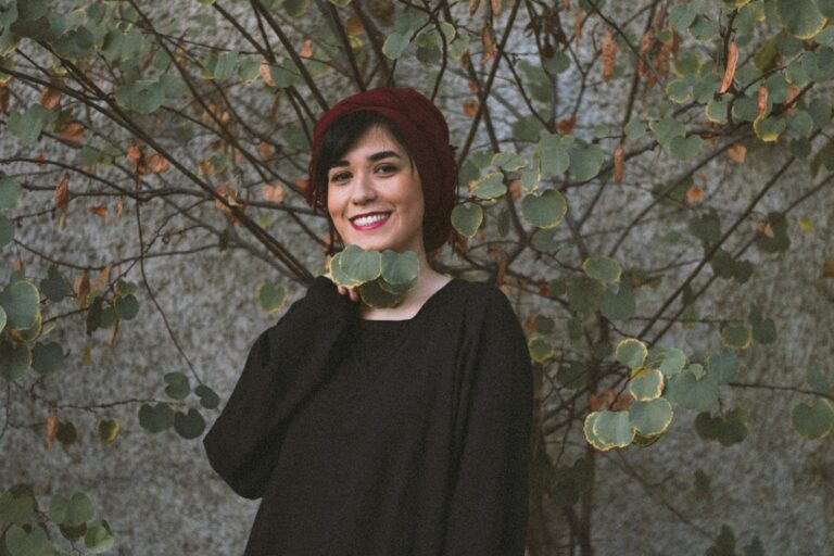 woman in black long sleeve shirt standing beside brown tree