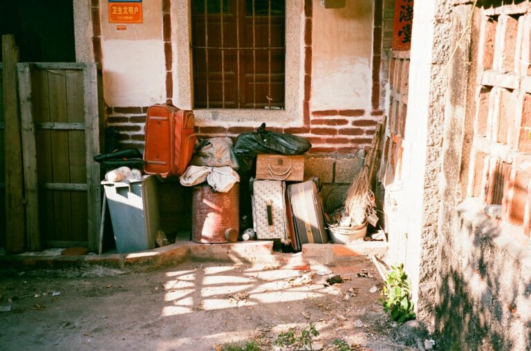 Stacked luggage and debris against a brick wall.