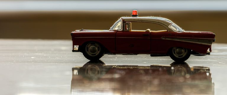 A vintage toy police car with red siren light.