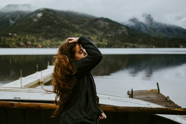 woman in black hoodie standing on brown wooden dock during daytime