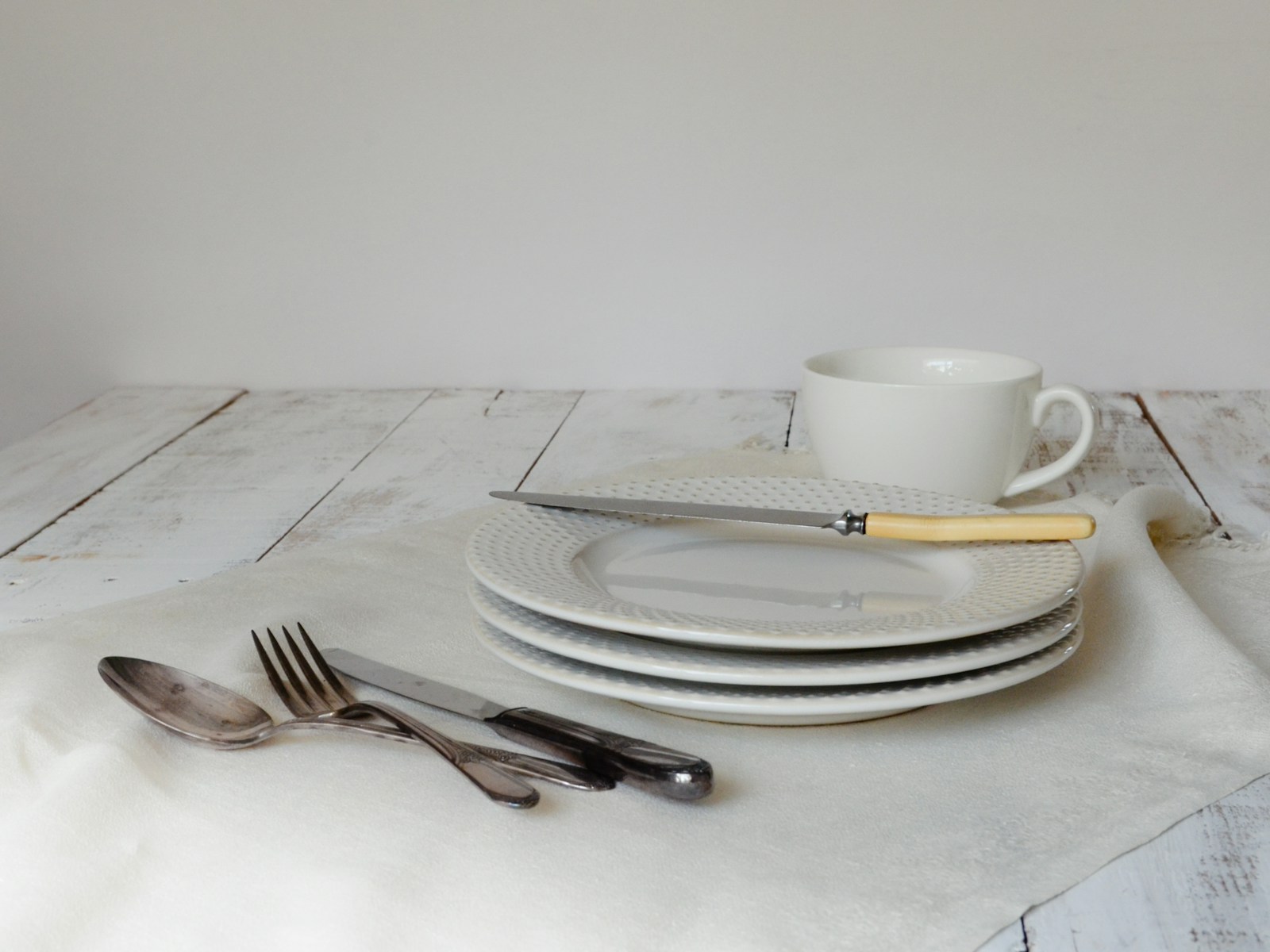 A white table topped with plates and silverware