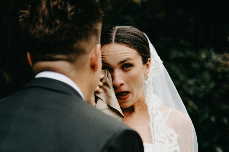 Bride cries while wiping eyes with cloth.