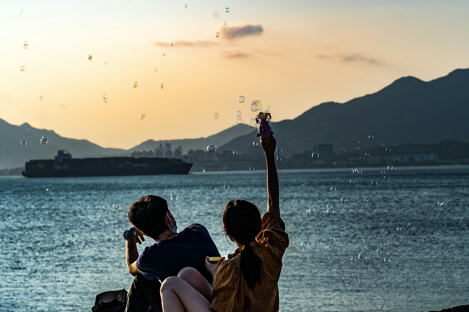 man and woman sitting on beach during sunset