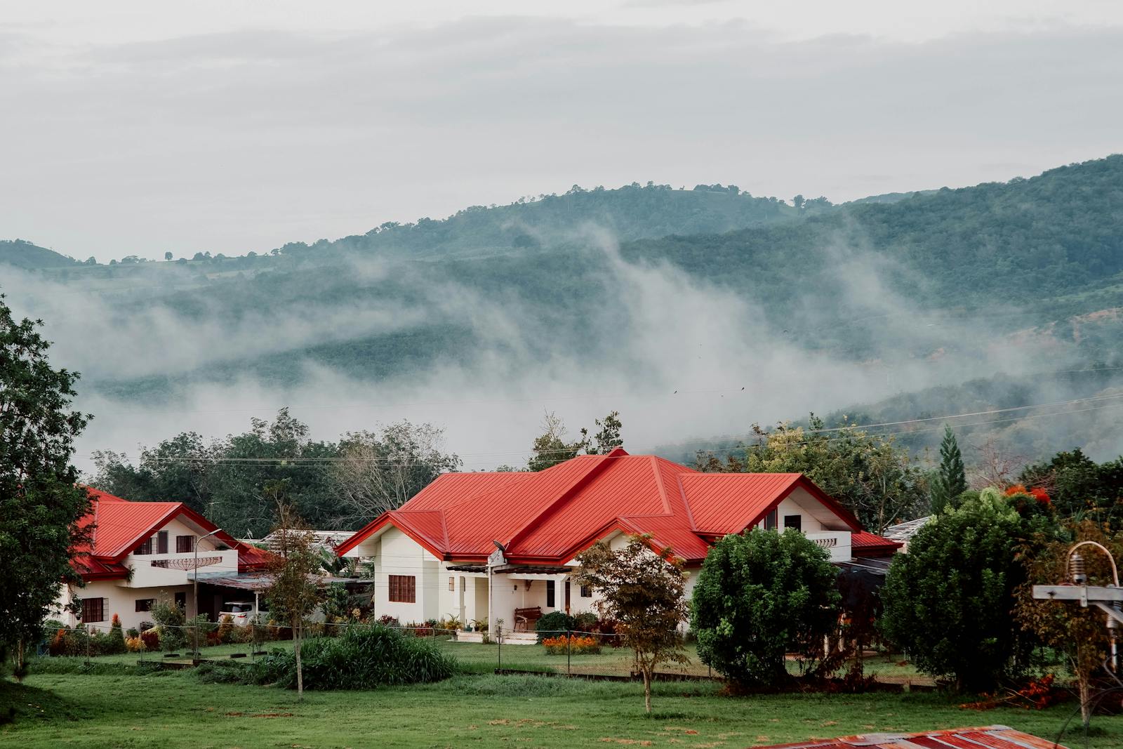 Charming rural houses with red roofs nestled in Valencia's misty mountainside landscape.