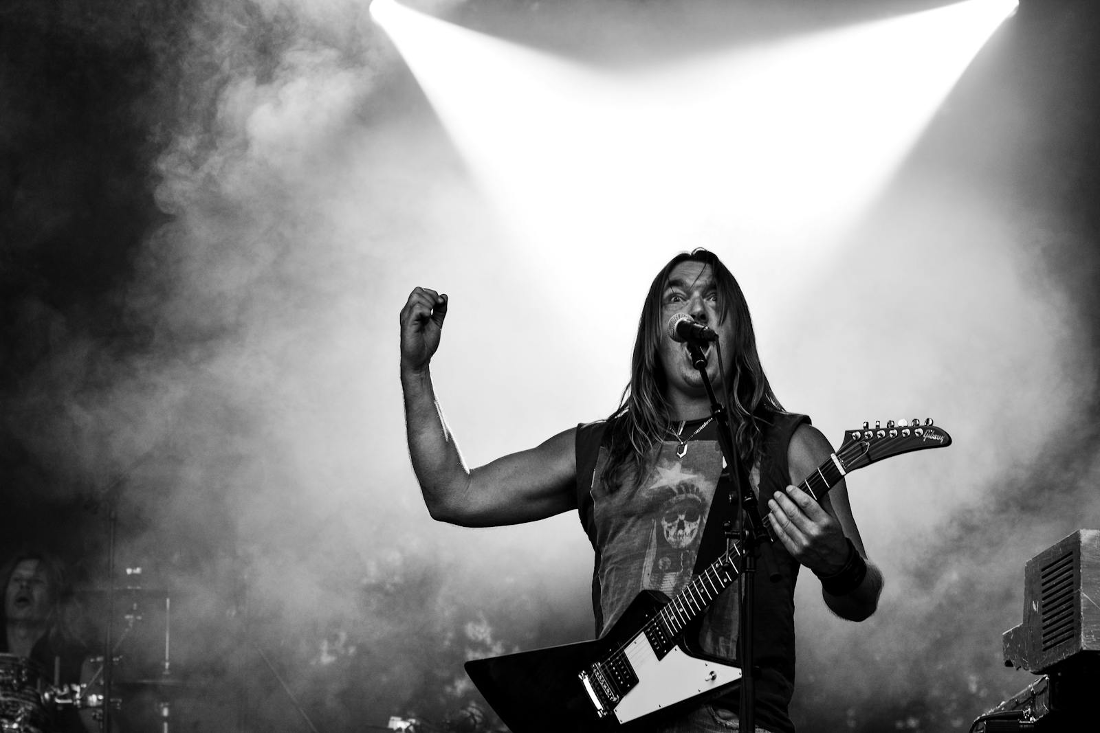 Black and white image of a rock musician playing guitar on stage during a dynamic concert performance.