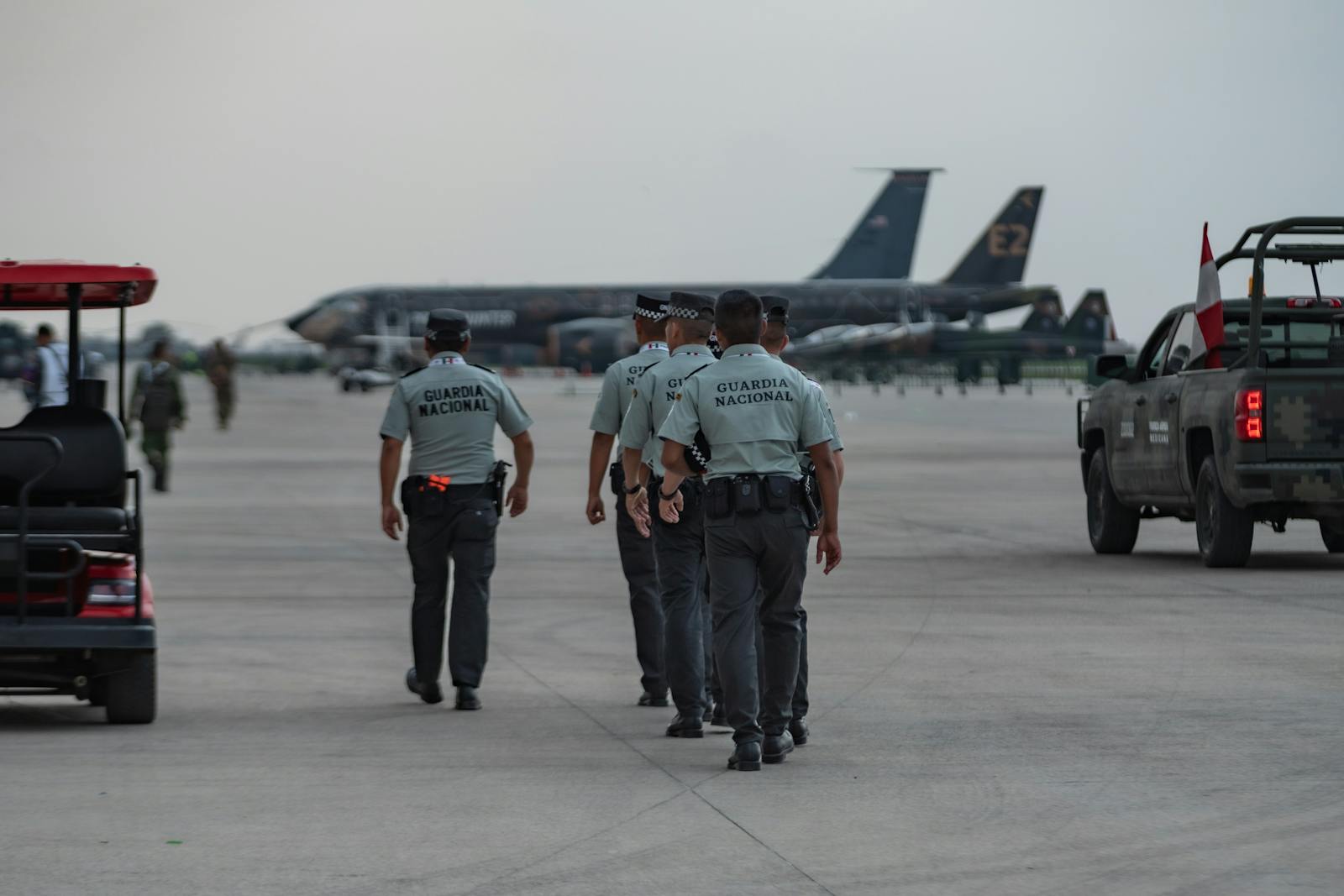 National Guard officers patrolling an airport tarmac with planes in the background.
