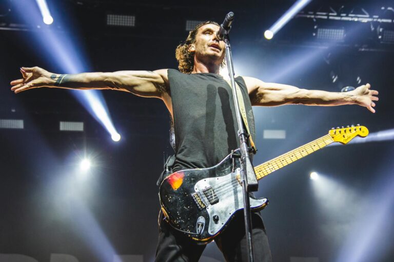 Musician passionately performing on stage with electric guitar under bright stage lights.