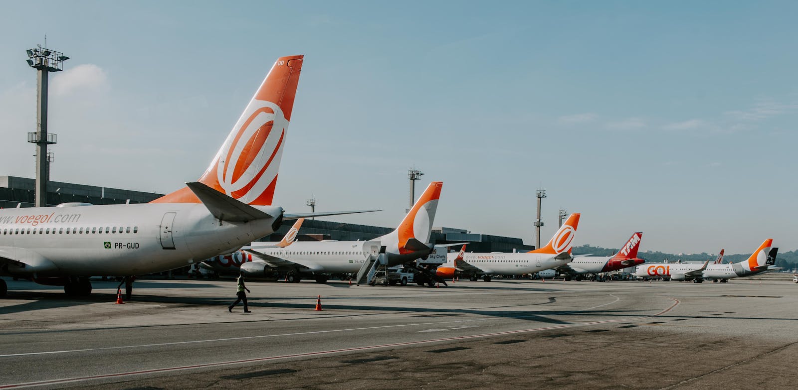 Multiple airplanes on tarmac at a busy airport during daytime, showcasing aviation and travel.