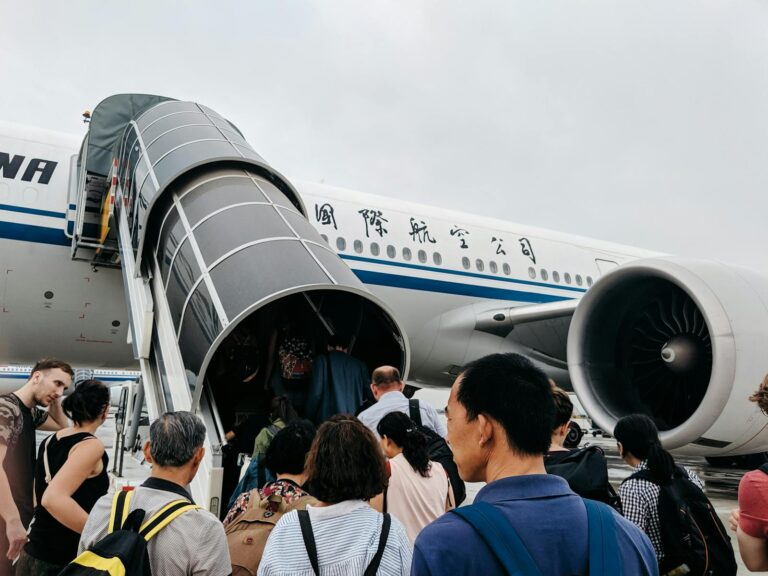 A group of people boarding an airplane via a jet bridge at Beijing Airport, China.