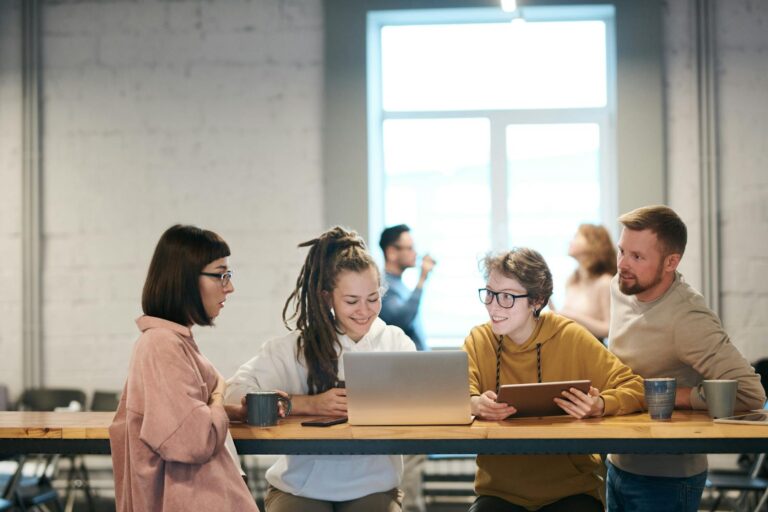 A group of young professionals collaborating indoors with laptops and tablets.