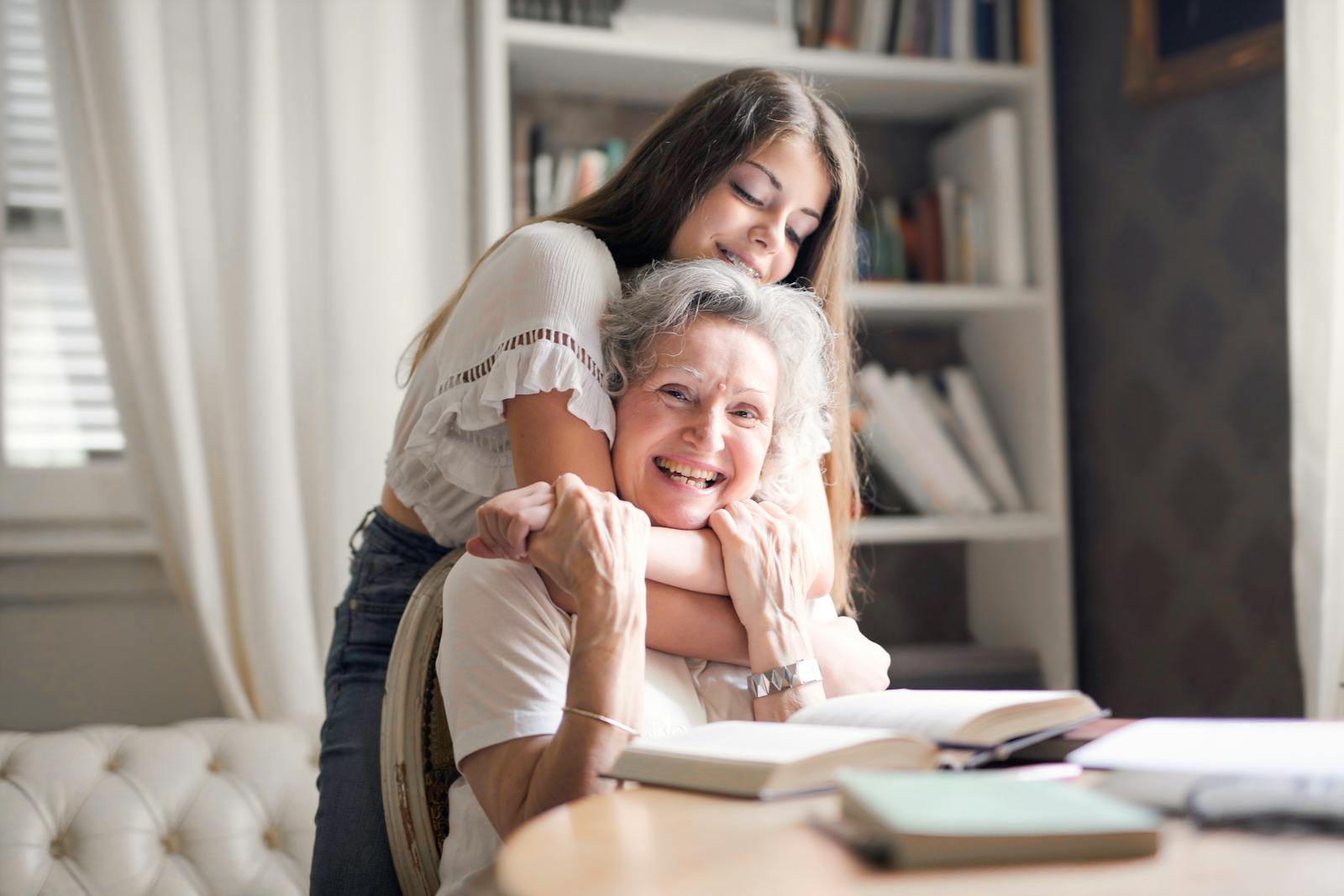 A joyful moment of a granddaughter hugging her grandma at home, showcasing love and family bond.