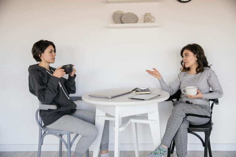 Two women enjoying a casual conversation with coffee in a cozy indoor setting, enhancing connections.