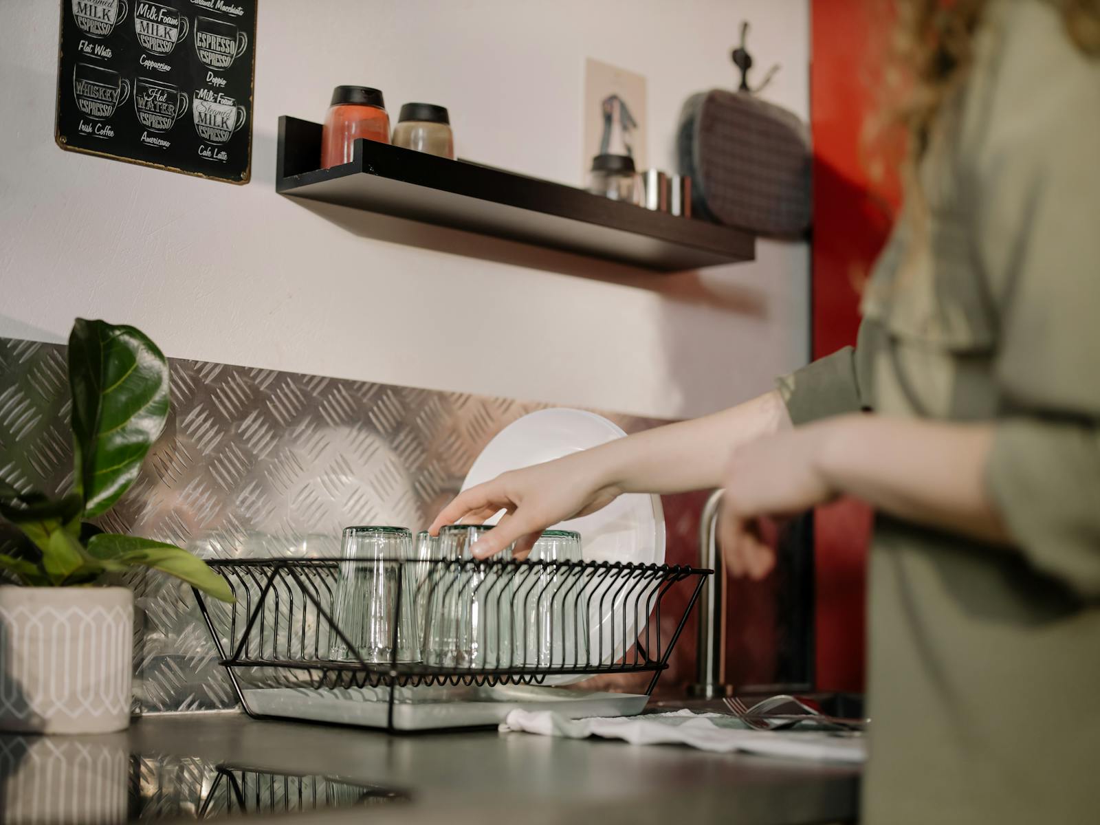 A woman arranging clean glasses in a modern kitchen setting, showcasing domestic organization.
