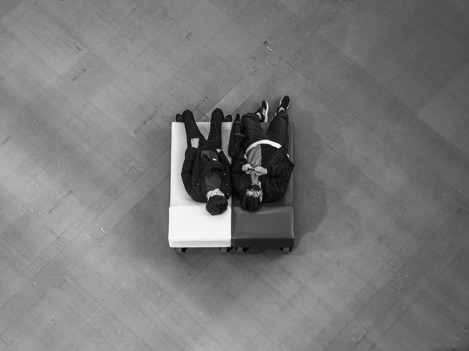 Two people lying on a luggage cart