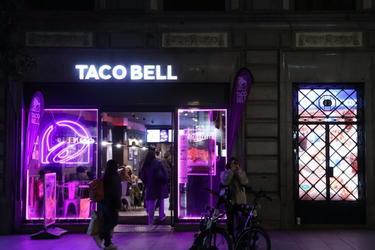 A purple lit store front with people walking by