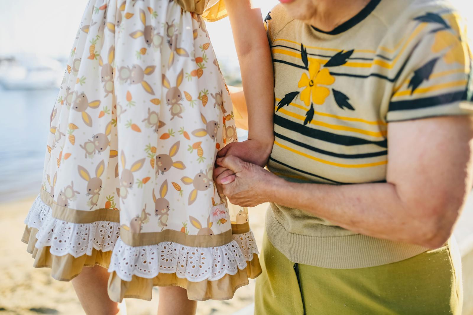 A loving moment between a grandmother and child holding hands on a sunny day.