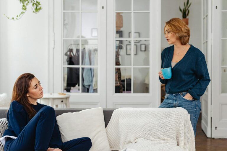 Two women in a cozy home setting having a casual conversation over coffee.