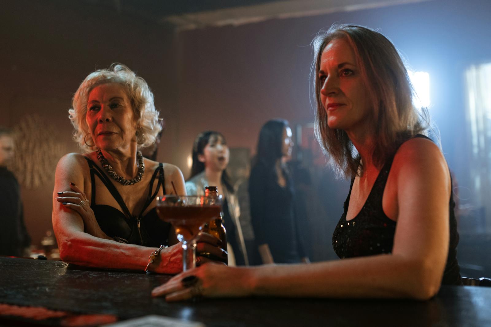 Two women sitting at a bar, enjoying a cocktail during a lively night out.