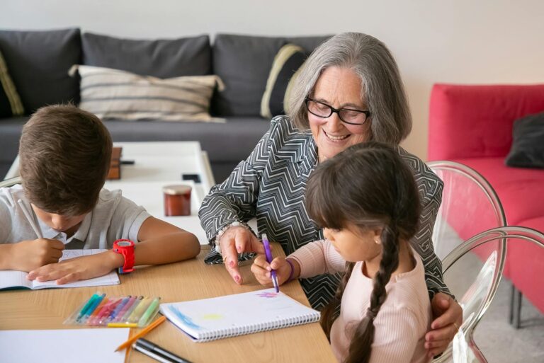 A joyful grandmother assists her grandchildren with their homework indoors.