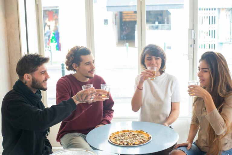 Four friends enjoying drinks and pizza in a cafe, capturing the essence of togetherness.