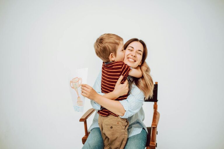 A joyful child hugging his smiling mother while holding a trophy drawing.