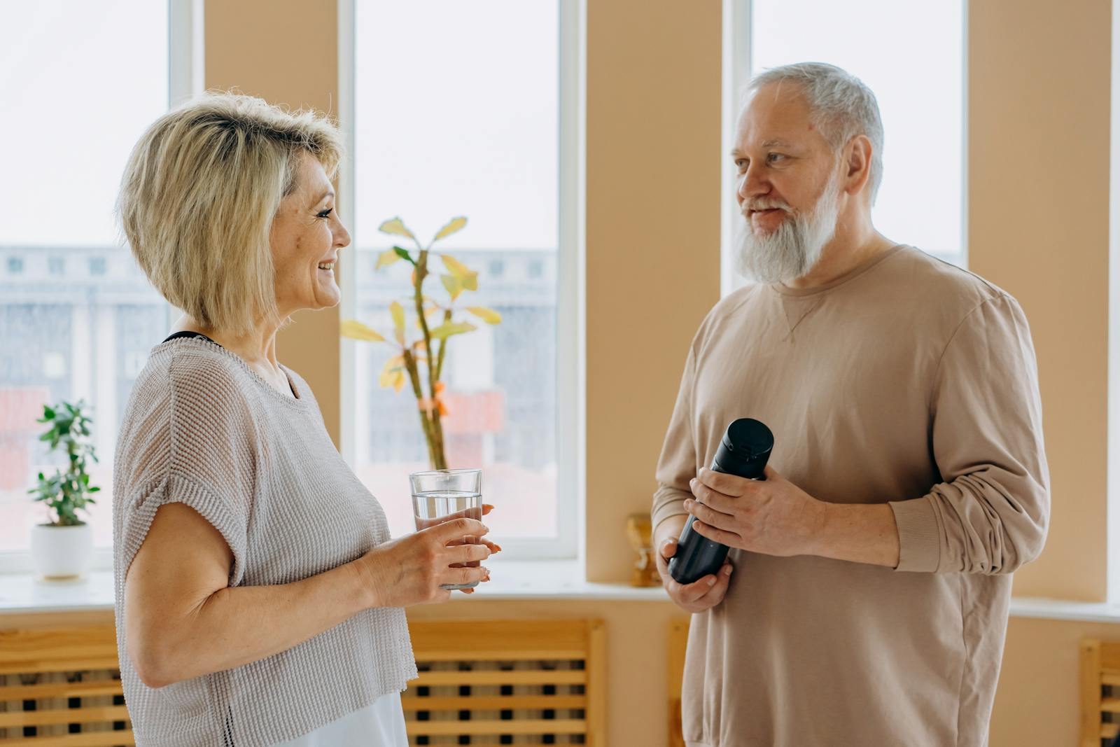 Elderly couple smiling and talking indoors, promoting a healthy lifestyle.