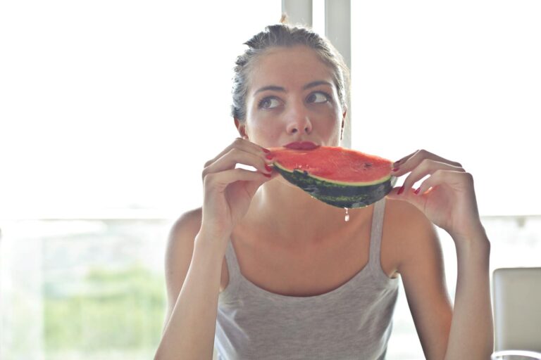 Portrait of a woman eating watermelon indoors, reflecting health and summer vibes.