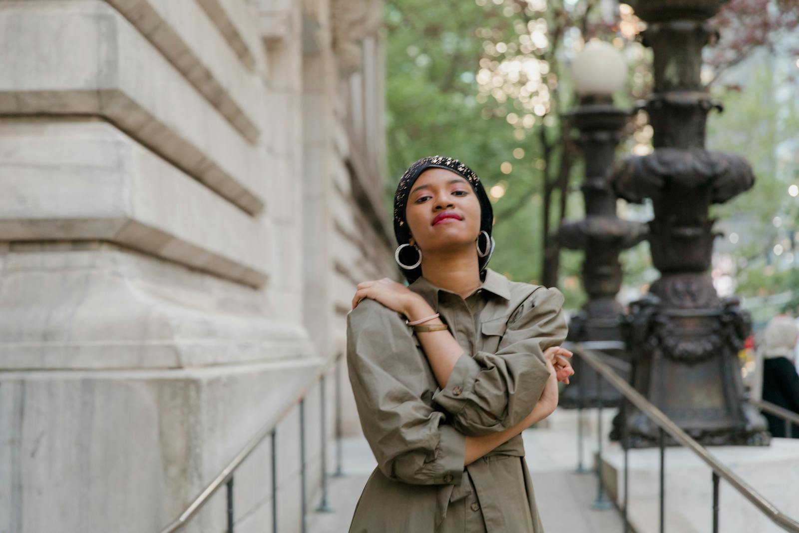 Confident woman in fashionable outfit posing outdoors against an urban architectural backdrop.