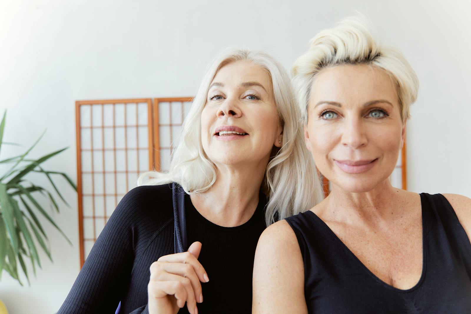 Two senior women smiling indoors, enjoying friendship and bonding. Bright, cheerful mood.