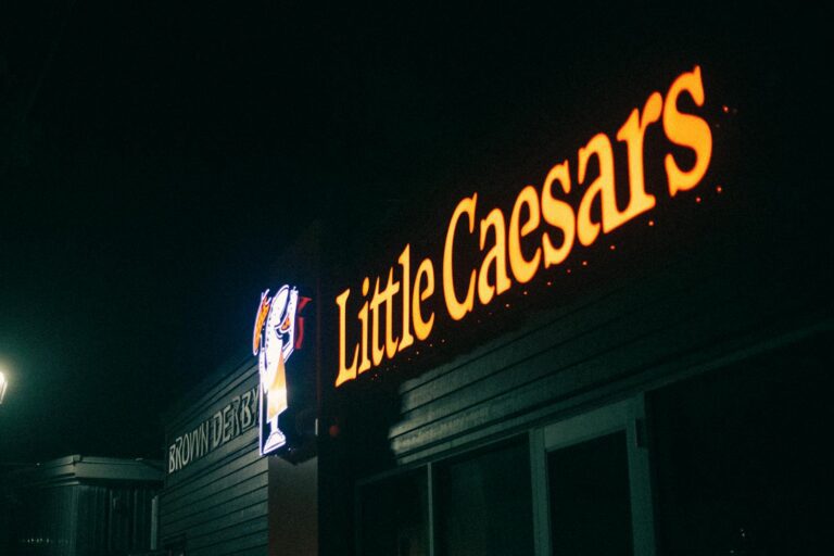 A dimly lit image of a Little Caesars restaurant sign glowing in the night.