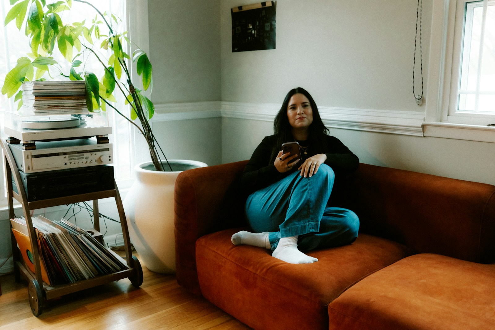 Woman sitting on couch with phone in hand.