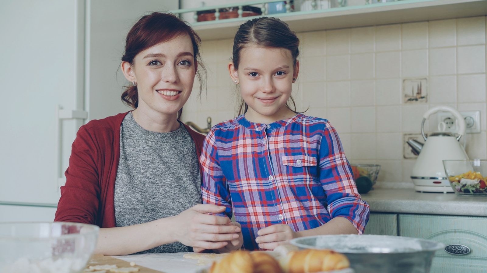 Mother and daughter are baking together in the kitchen.