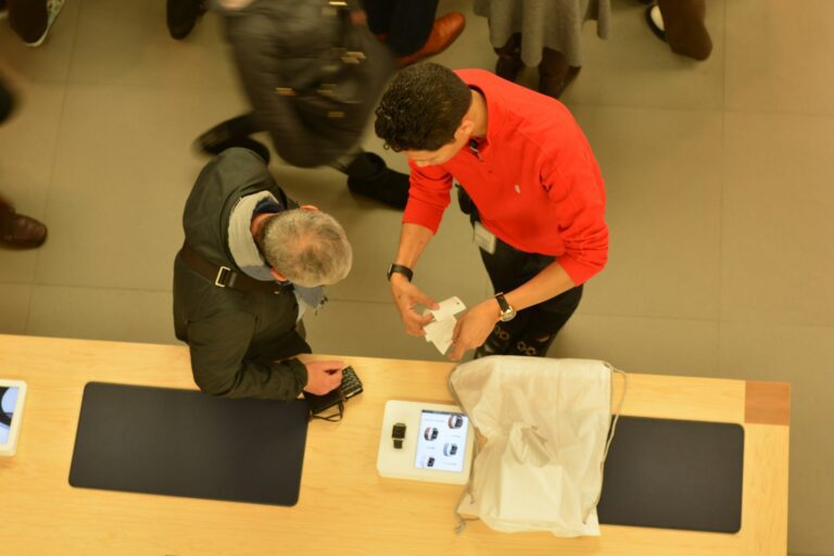 A store employee helps a customer at a counter.