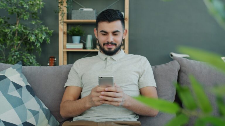 Man sitting on couch using smartphone