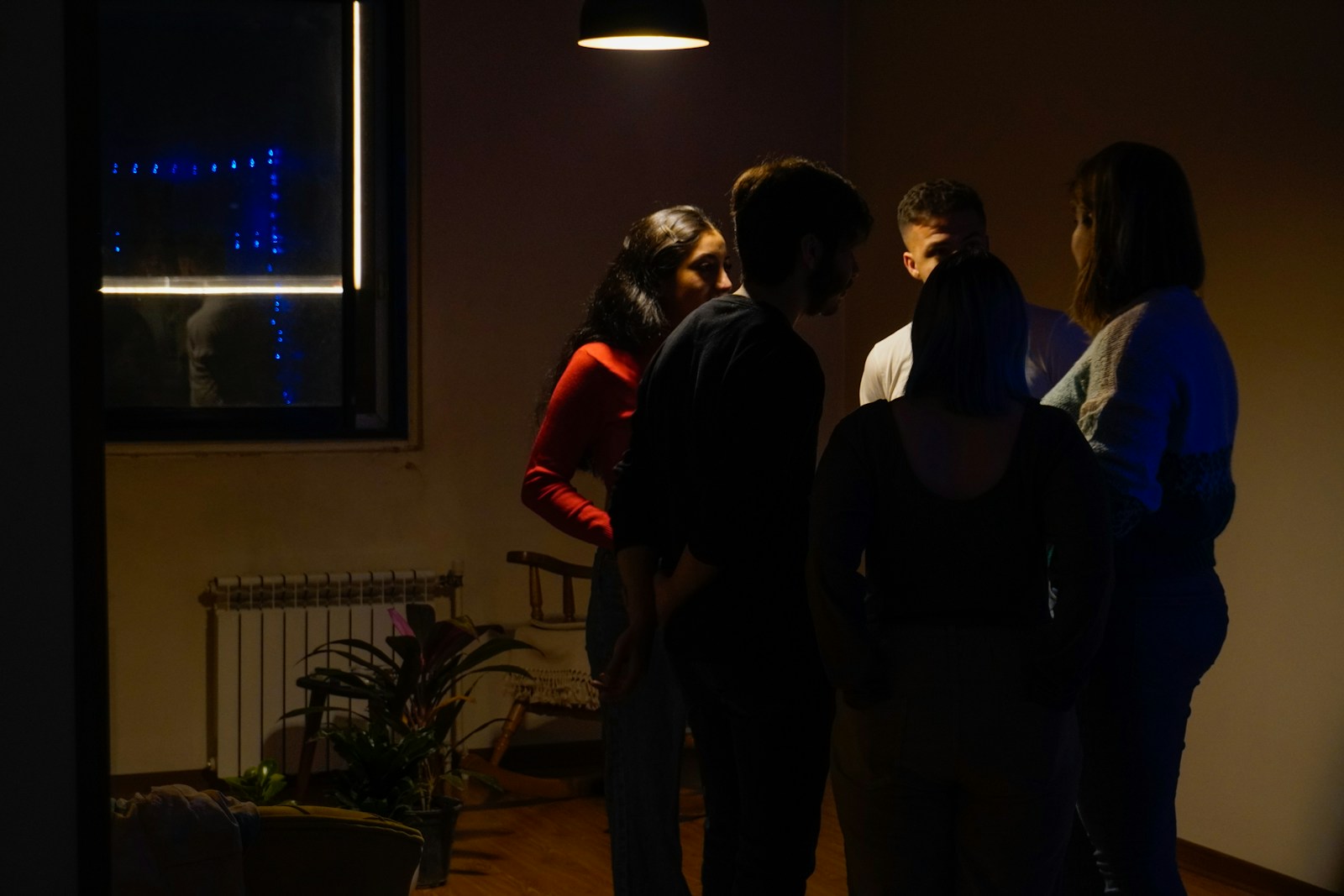 Friends gather in a dimly lit room.