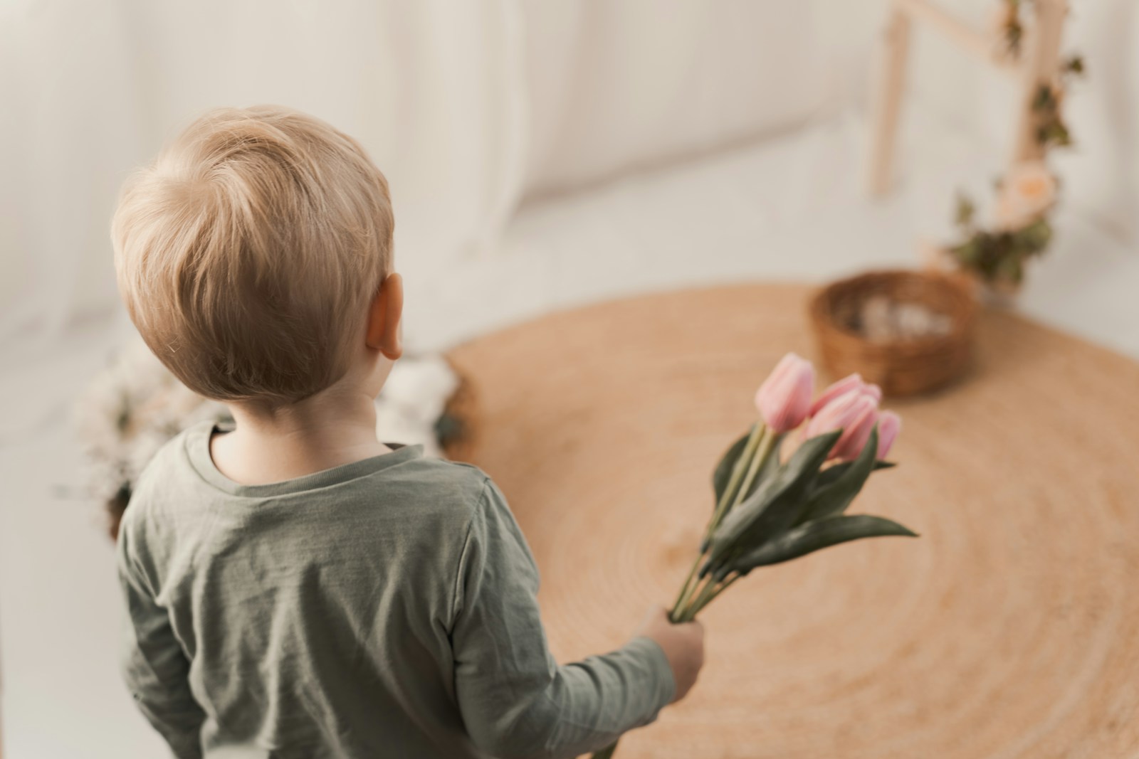 A young boy holding pink tulips indoors