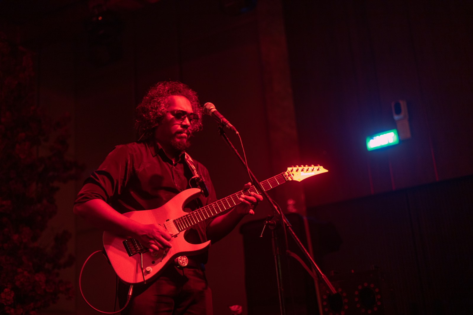 Man playing electric guitar on stage with red lighting