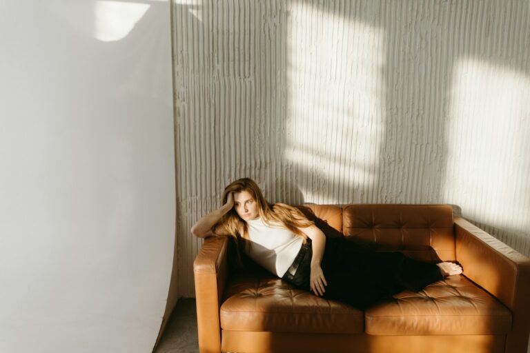 A woman relaxes on a brown couch.