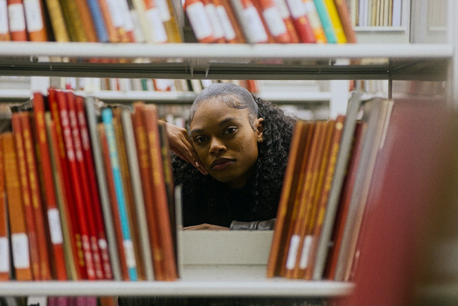 Young woman looking through bookshelves in a library