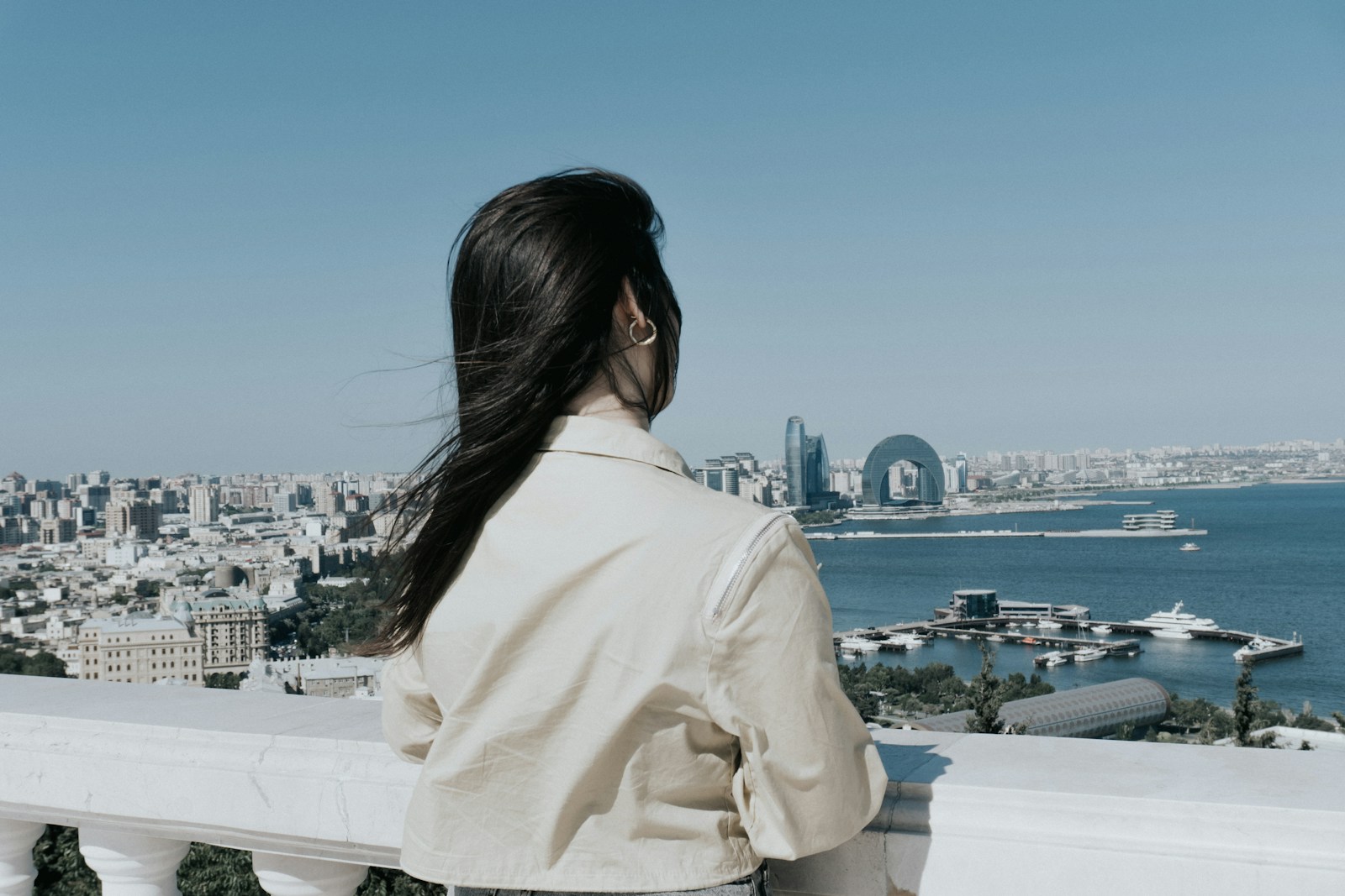 Woman enjoys the city view from a balcony.