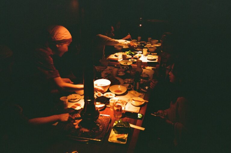 a group of people sitting at a table with plates of food