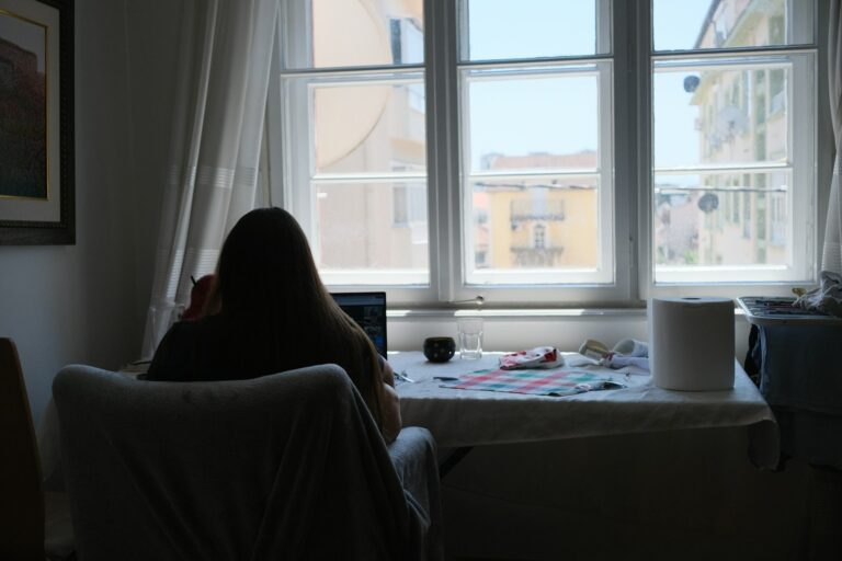 Person works near a bright window in a room.