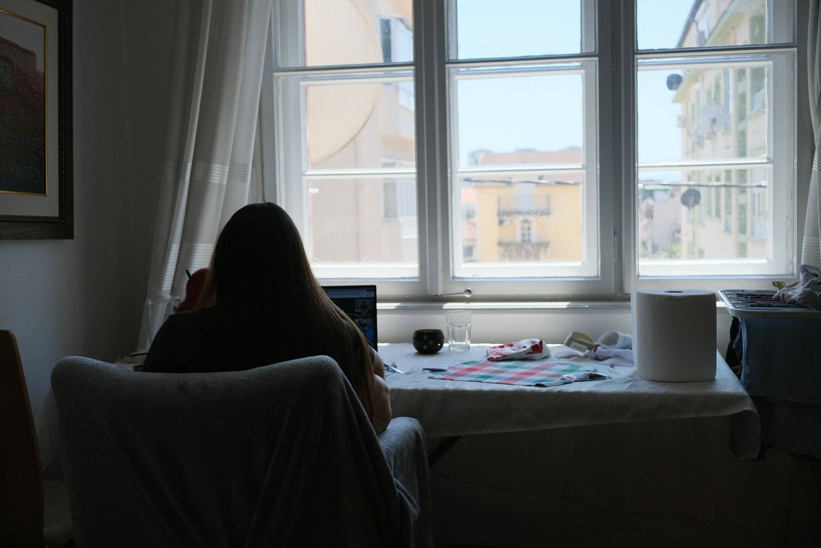 Person works near a bright window in a room.
